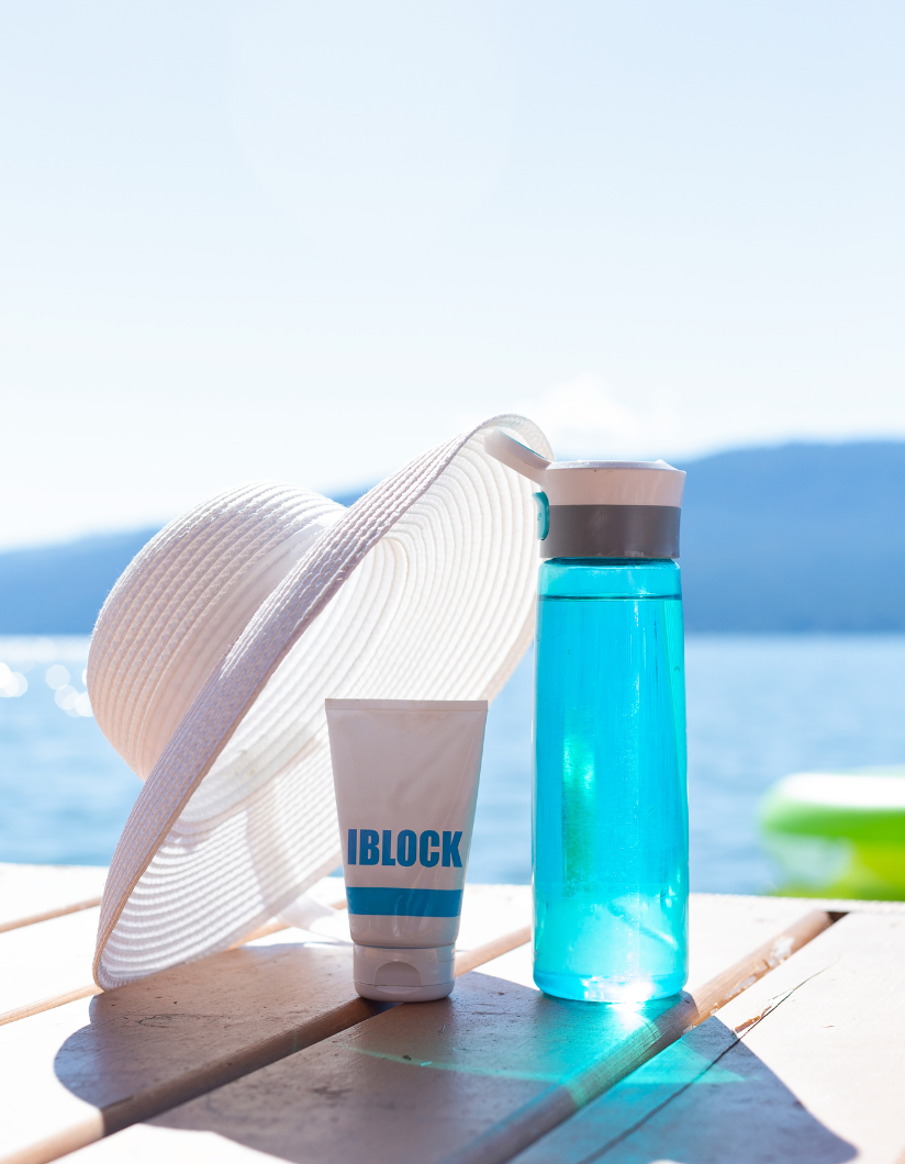 Sommerausstattung am Wasser Sonnenhut, Sonnencreme und Trinkflasche am See – typische Sommer Werbeartikel im Einsatz für Outdoor-Kampagnen