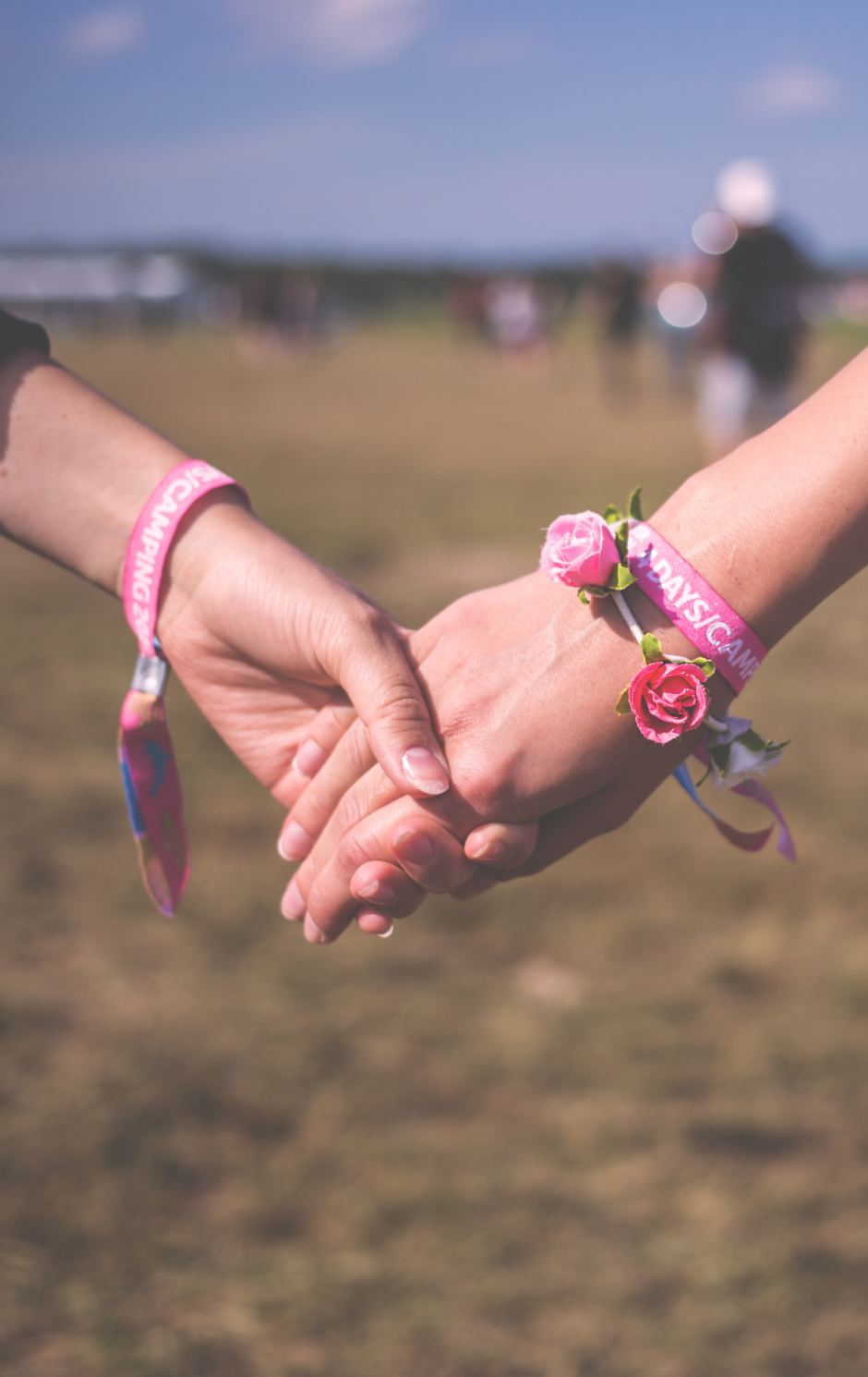 Zwei Hände mit bunten Festivalarmbändern und Blüten Festival Give Aways wie personalisierte Stoffarmbänder – beliebtes Accessoire für Musik-Events, Messen oder Jugendkampagnen.